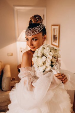 Güzel, mutlu, genç gelin elinde bir buket çiçek tutuyor.     