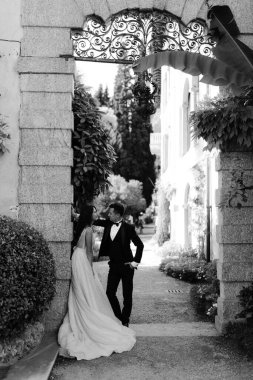 Gelin ve damadın açık havada yürürken siyah ve beyaz görüntüsü. 