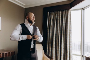 Resmi takım elbiseli genç yakışıklı adam odada poz veriyor.