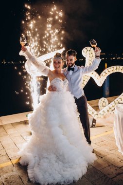 Mutlu bir düğün çifti kutlama yapıyor ve akşamları şarap içiyorlar.