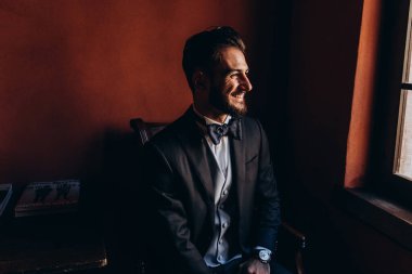 Resmi takım elbiseli genç yakışıklı adam odada poz veriyor.