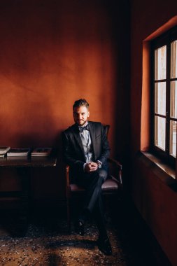 Resmi takım elbiseli genç yakışıklı adam odada poz veriyor.