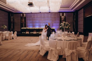 Güzel, mutlu bir düğün çifti restoranda sarılıyor ve poz veriyor..