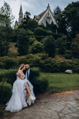 Mutlu genç gelin ve damat parkta birlikte oturup sarılıyorlar.