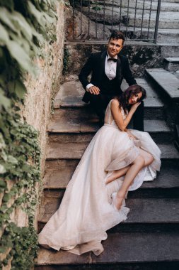 Eski kasabadaki merdivenlerde poz veren mutlu genç bir çiftin portresi.                           