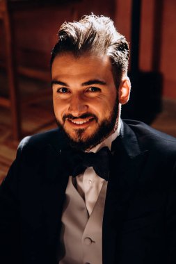 Odada takım elbiseli yakışıklı bir genç var.