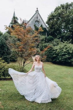 Beyaz elbiseli gelin parkta poz veriyor.