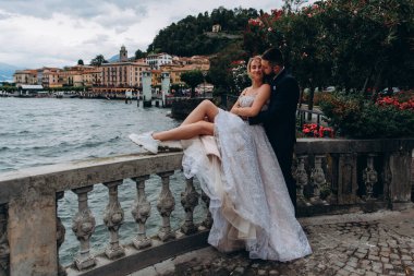 Güzel, mutlu, genç bir çift dağ gölü kenarında sarılıp öpüşüyor.