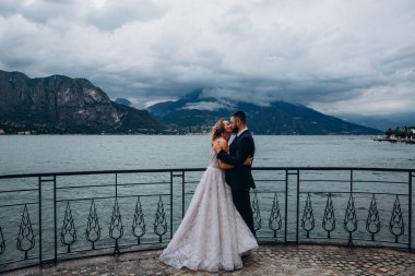 Güzel, mutlu, genç bir çift dağ gölü kenarında sarılıp öpüşüyor.  