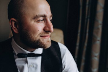 Zarif takım elbiseli ve papyonlu yakışıklı genç damat portresi.     