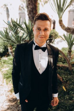 Botanik bahçesinde takım elbiseli ve papyonlu genç adam. 