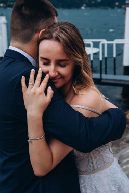 Gelin ve damat göl kıyısında sarılıyor. 