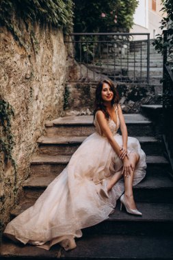 Gelinlikli güzel gelinin portresi. Eski kasabadaki merdivenlerde poz veriyor.                       