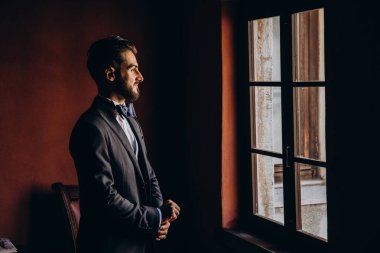 Yakışıklı, düşünceli genç damat sabahları pencereye bakıyor.   