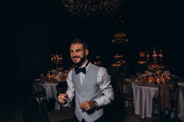 Şık mutlu damat düğün resepsiyonunda dans edip gülümsüyor.