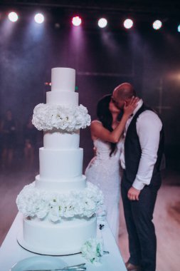 Güzel, genç bir çift yeni evli öpüşüyor, düğün pastasını yakından görüyor.