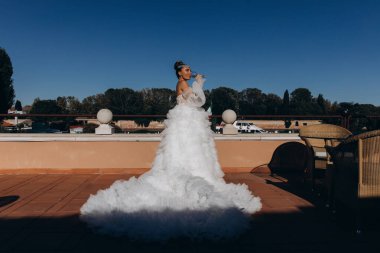 Gelinlikli güzel gelin güneşli bir günde havuz kenarında şarap içiyor.    