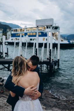 Birbirine aşık genç bir çift dağ gölünün kıyısında sarılıyor.