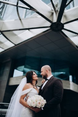 Beyaz elbiseli güzel gelin ve şehirde birbirine gülümseyen yakışıklı damat.