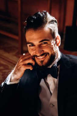 Klasik takım elbiseli ve papyonlu şık genç adam kameraya gülümsüyor.