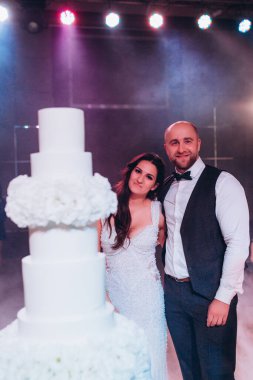 Düğün pastasıyla poz verip sarılan gelin ve damat çifti..