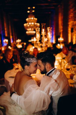 Gelin ve damat düğünü kutluyor, kucaklaşıyor ve birlikte oturuyorlar.