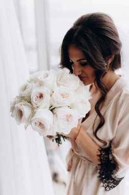 Güzel, mutlu, genç gelin elinde bir buket çiçek tutuyor.    