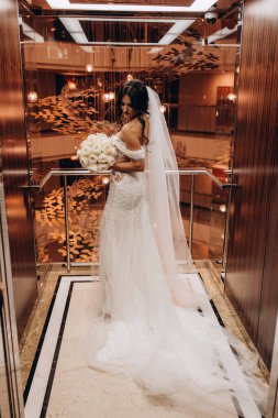 Lüks içinde poz veren düğün buketli çekici gelin.