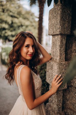 Gelinlikli güzel gelin kameraya gülümsüyor ve sokakta poz veriyor.   