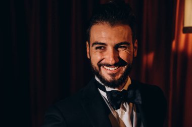 Zarif takım elbiseli ve papyonlu yakışıklı genç damat portresi.     