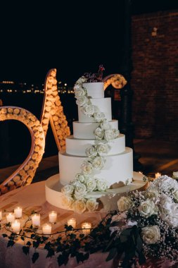 Geceleri gül ve mumlarla düğün pastası.     