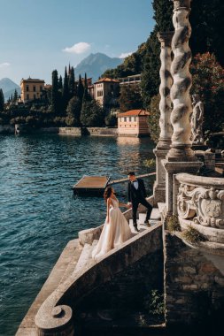 Gelin ve damat el ele tutuşup denizde merdivenlerde yürüyorlar.