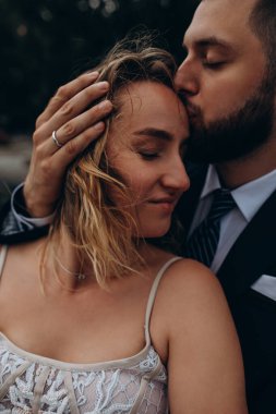 Birbirlerini kucaklayan ve öpen güzel mutlu çiftin yakın çekimi.