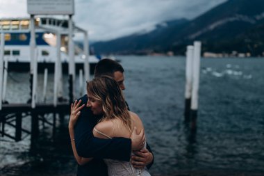 Güzel, mutlu, genç bir çift göl kenarında kucaklaşıyorlar.              