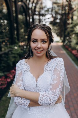 Güzel gelinin portresi parkta duruyor ve kameraya gülümsüyor.