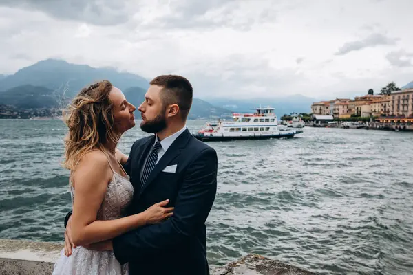 Genç gelin ve damat dağ gölünde öpüşüyorlar.  