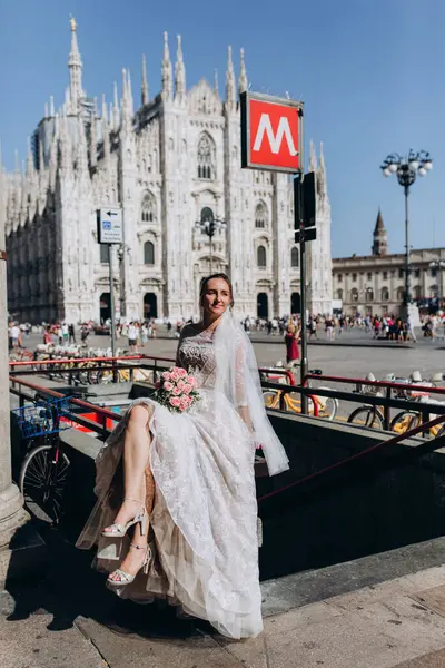 Şehir sokaklarında poz veren bir buket çiçekli mutlu gelin.  