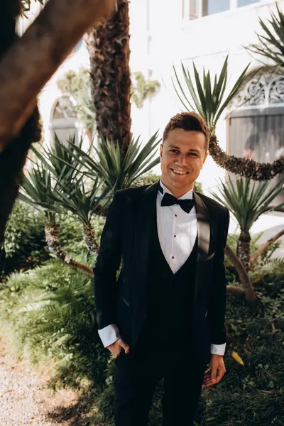 Botanik bahçesinde takım elbiseli ve papyonlu genç adam. 