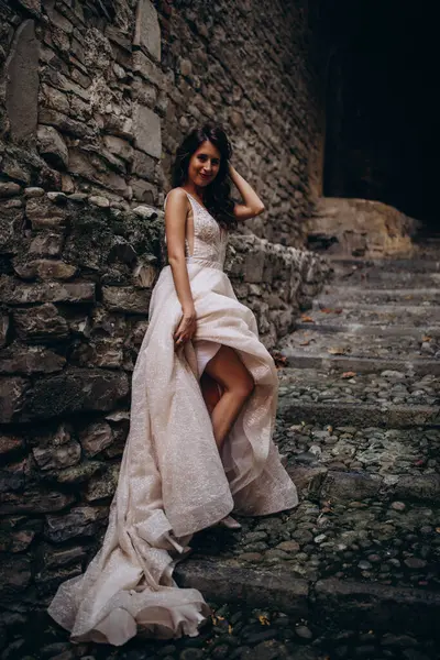 Gelinlikli güzel gelinin portresi. Eski kasabadaki merdivenlerde poz veriyor.                       