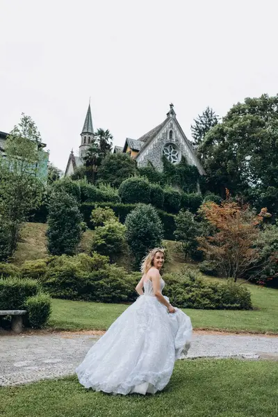 Yeşil parkta poz veren beyaz gelinlikli güzel gelin.