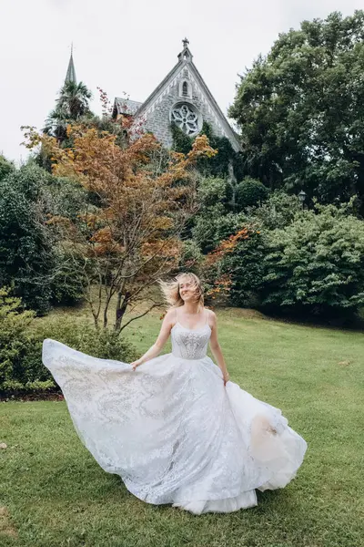 Beyaz elbiseli gelin parkta poz veriyor.