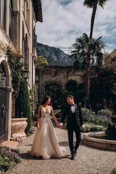 Genç bir çift gelin ve damat eski evin önünde poz veriyorlar. Yeni evlilerin düğün günü.