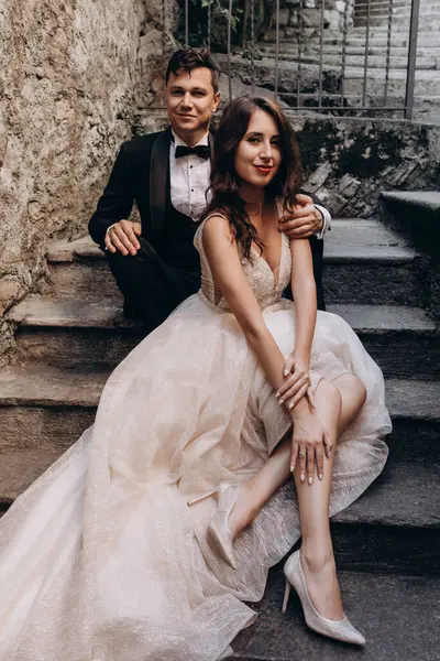 Eski kasabadaki merdivenlerde poz veren mutlu genç bir çiftin portresi.                           