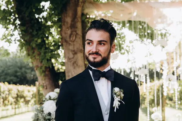 Parkta gülümseyen genç damadın portresi.