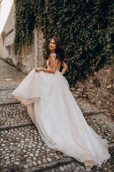 Gelinlikli güzel gelinin portresi. Eski kasabadaki merdivenlerde poz veriyor.                       