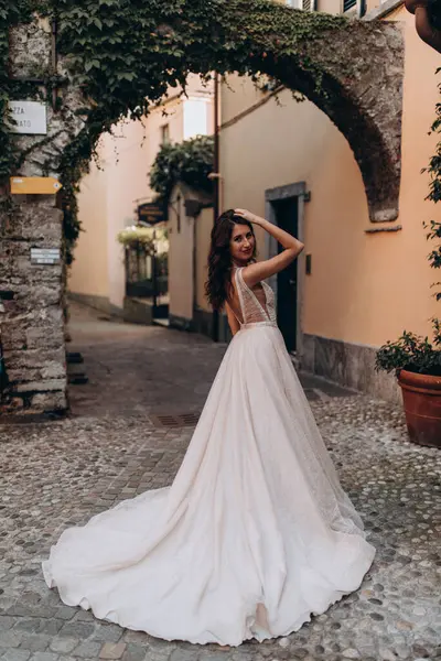 Beyaz gelinlikli güzel gelin eski kasaba caddesinde poz veriyor.                