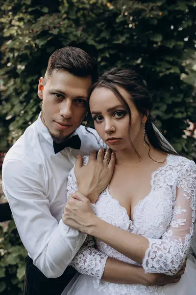 Güzel mutlu gelin ve damat parkta kucaklaşıyorlar.      