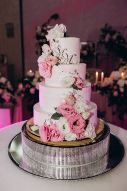 Çiçeklerle süslenmiş lezzetli düğün pastasının yakın çekimi.              