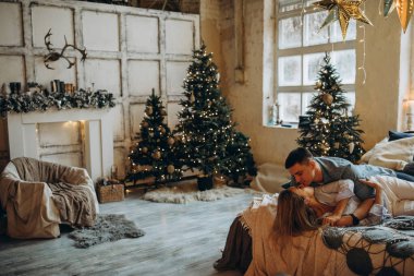 Genç çift yatakta yatıyor, stüdyo Noel dekoruyla 