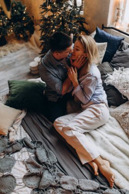 Genç çift yatakta yatıyor, stüdyo Noel dekoruyla 